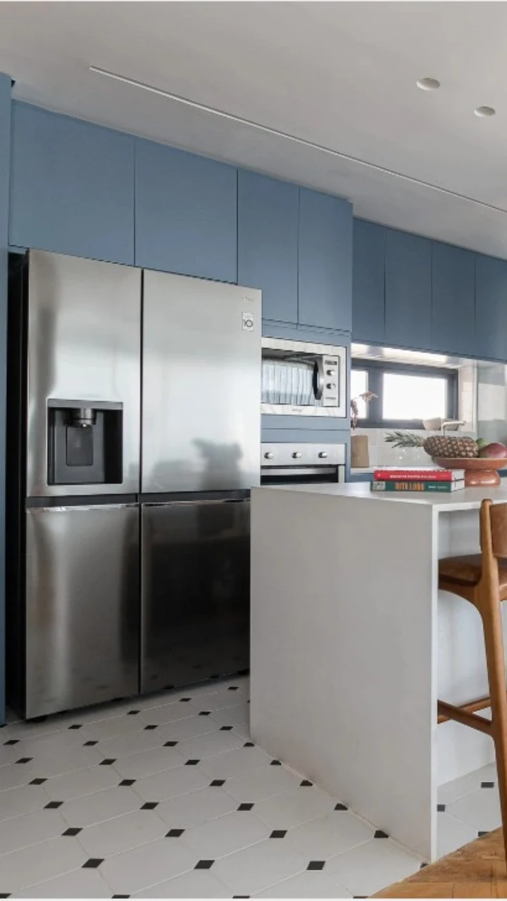 Cozinha planejada em tom azul com geladeira embutida